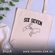 Шопер six seven жест руками, бежевий, на столі, з рослинами, бренд Згадка.