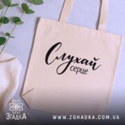 Шопер слухай серце, бежевий, на столі з рослинами, бренд Згадка.