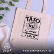 Шопер Тато найкращий чоловік, бежевий, зверху, зелений фон, бренд Згадка.