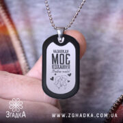 Жетон моє кохання, чорний з матовою поверхнею, зображення на білому фоні, ракурс збоку, фон з розмитими кольорами, видно руку, що тримає жетон.