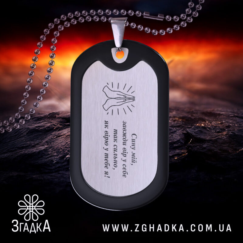 Жетон оберіг для сина, чорний з матовою поверхнею, з дзеркальним сріблястим центром, фон червоний та чорний, видно кулю та частину ланцюжка.