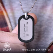 Жетон подарунок коханому чоловіку. Жетон чорного кольору з матовою поверхнею, вид з близька, фон з розмитими кольорами, видно руку, що тримає жетон.