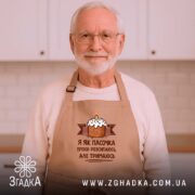 Фартух я як пасочка але тримаюсь, бежевий, на чоловікові, кухня на фоні,.