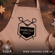 Фартух майстер краси, бежевий, на дерев'яному фоні, з логотипом Згадка.