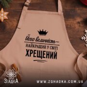 Фартух найкращий у світі хрещений, бежевий, на дерев'яному фоні, бренд Згадка.