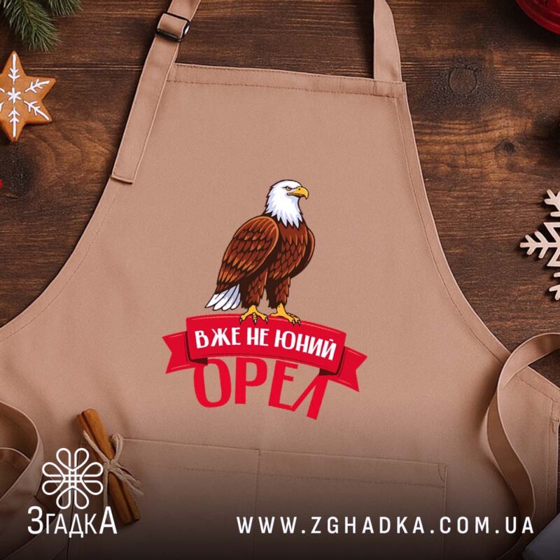 Фартух вже не юний орел, бежевий фон, на дерев'яному столі, бренд Згадка.