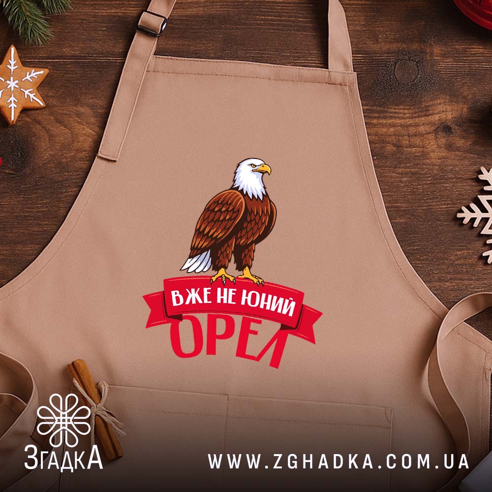 Фартух вже не юний орел, бежевий фон, на дерев'яному столі, бренд Згадка.