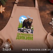 Фартух залишайся диким ведмежий принт, бежевий фон, дерев'яний стіл, бренд Згадка.