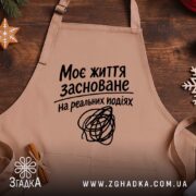 Фартух життя на реальних подіях, бежевий, на дерев'яному фоні, бренд Згадка.