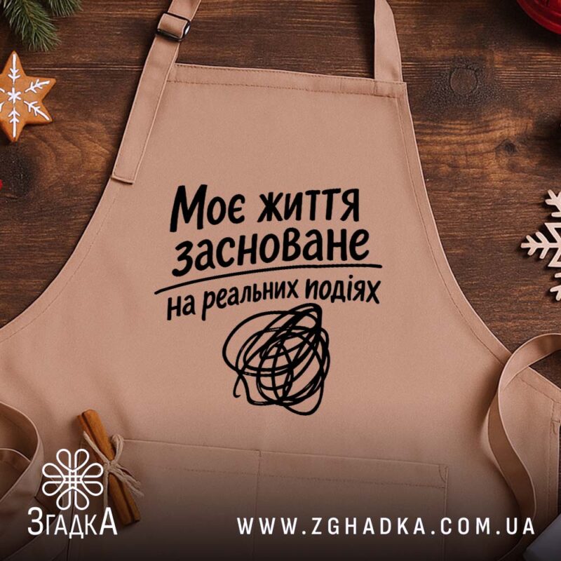 Фартух життя на реальних подіях, бежевий, на дерев'яному фоні, бренд Згадка.