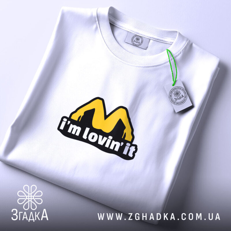 Футболка I’m lovin’ it на столі, білий фон, деталі принта чіткі, бренд.