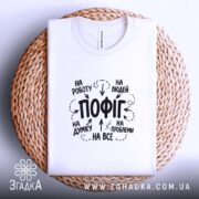 Футболка пофіг на все, біла, складена на кошику, принт на тканині, бренд.