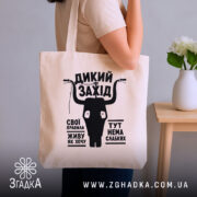 Шопер дикий захід у руках, бежевий колір, принт на фоні кімнати, бренд.