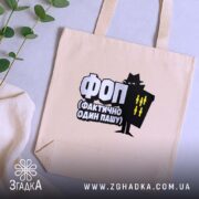 Шопер ФОП Фактично Один Пашу, бежевий, на столі з рослинами, бренд Згадка.