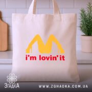 Шопер I’m lovin’ it подарунок, бежевий, на столі, з жовтим принтом, бренд.
