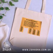 Шопер котик на годину, бежевий, з жовтим принтом, на фоні рослин, бренд.