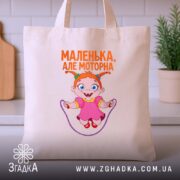 Шопер маленька але моторна, бежевий, з принтом дівчинки, на кухонному фоні, бренд.