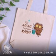 Шопер мамі потрібна кава, бежевий, на фоні рослин, з принтом сови, бренд.