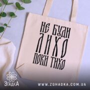 Шопер не буди лихо поки тихо, бежевий, на столі, зелений декор, бренд.