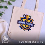 Шопер виховую чемпіонів, бежевий на столі, бренд Згадка.