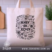 Шопер живу як хочу, бежевий, на фоні кухні, з принтом, бренд Згадка.