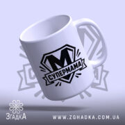 Чашка cупермама найкраща мама Чашка супермама найкраща мама, під кутом з глянцевим.