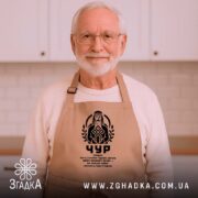 Фартух Чур слов’янський захисник, бежевий, на літньому чоловікові в кухні, бренд Згадка.