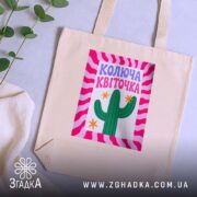 Шопер колюча квіточка на бежевому фоні, лежить на столі з рослиною, бренд.