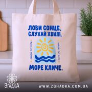 Шопер розквітай навіть після бурі, бежевий на кухонному фоні, яскравий принт, бренд.