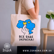 Шопер все буде Україна, бежевий, на руці, з квітами на фоні, бренд.