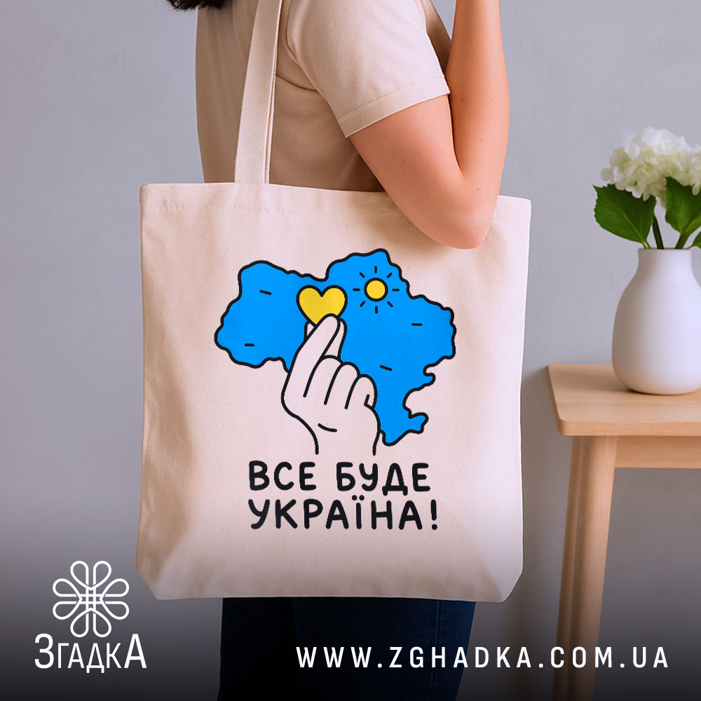 Шопер все буде Україна, бежевий, на руці, з квітами на фоні, бренд.