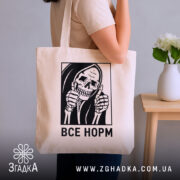 Шопер все норм скелет, бежевий, на плечі у моделі, фон нейтральний, бренд.
