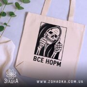 Шопер все норм скелет, бежевий, на столі з рослинами, бренд Згадка.