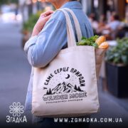 Шопер wander more для любителів гір, бежевий, з продуктами, на вулиці, бренд.