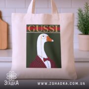 Шопер з принтом gussi, бежевий, на столі, фон з кухонними предметами, бренд.