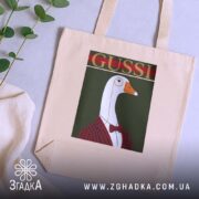 Шопер з принтом gussi, бежевий, на столі, фон з рослинами, бренд Згадка.
