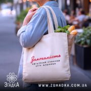 Шопер закоханість офіційний спонсор, бежевий, на плечі, фон вулиця, містить продукти, бренд.