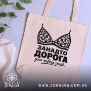 Шопер занадто дорога для твоїх очей, бежевий, на столі, зелена рослина, бренд.