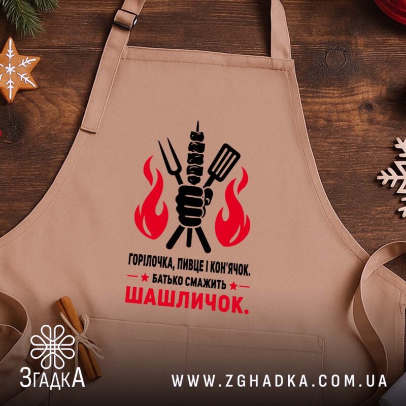 Фартух батько смажить шашличок, бежевий, на дерев'яному фоні, бренд Згадка.