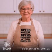 Фартух як старий дід, бежевий, на жінці з сивим волоссям, текст чорного.