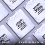 Футболка різка і неприємна, біла, на столі, кілька штук, принт чорний, бренд.