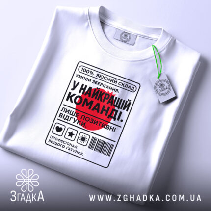 Футболка у найкращій команді, складена, біла, з етикеткою, принт з текстом, бренд.