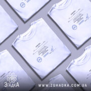 Футболка довідка психічне здоровʼя, біла, на столі, кілька футболок, бренд Згадка.