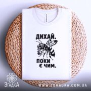 Футболка дихай поки є чим, складена на кошику, біла, принт з бджолою,.