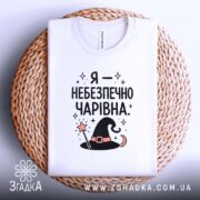 Футболка я небезпечно чарівна, складена, біла, на кошику, принт з шапкою, бренд.