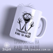 Чашка тримаюся на каві та надії, біла з принтом, бренд Згадка.