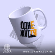 Чашка з принтом одне життя, нахилена, ручка зліва, фон світло-сірий, бренд Згадка.