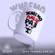 Чашка живемо лише раз, нахилена, глянцевий край, фон світло-сірий, бренд Згадка.