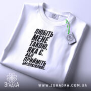 Футболка любіть мене такою яка є, біла, на столі, з етикеткою, бренд.