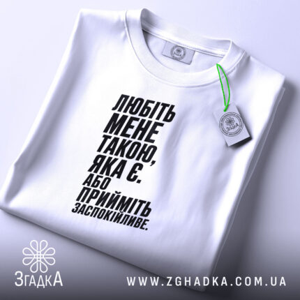 Футболка любіть мене такою яка є, біла, на столі, з етикеткою, бренд.